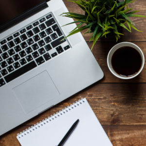 work space of a businessman. view from above . coffee notebook and laptop on the desktop with black note.